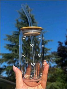 a person holding up a glass with straws in it and hearts drawn on the side