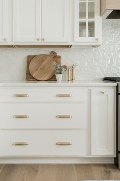 a kitchen with white cabinets and wooden cutting board on the top of the cabinet doors