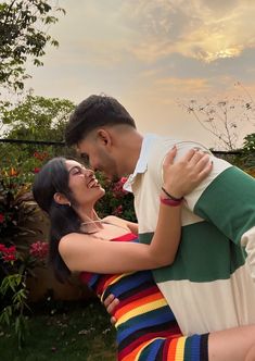 a man and woman embracing each other in front of flowers