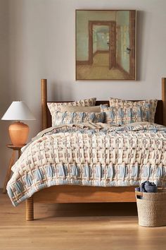 a bed sitting in a bedroom next to a lamp and pictures on the wall above it