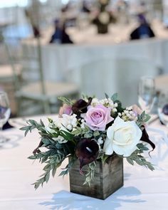 a vase filled with flowers sitting on top of a white table cloth covered dining room