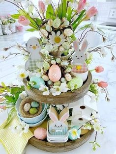 a three tiered tray filled with easter decorations and flowers on top of a table