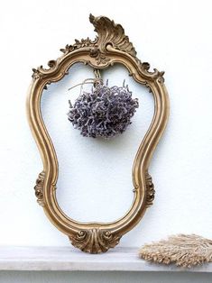 an ornate gold framed mirror sitting on top of a white mantle next to a dried lavender ball