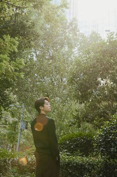 a man standing in the middle of a forest looking up into the sky with his eyes closed