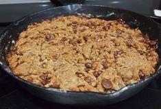 a skillet filled with oatmeal and chocolate chip cookies on top of a stove