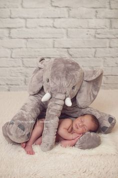 a baby laying on top of an elephant stuffed animal