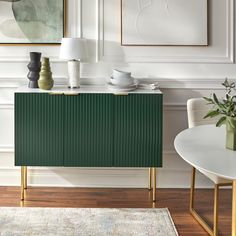 a green cabinet in a white room next to a table with two vases on it