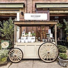 an old fashioned ice cream cart with wheels on the sidewalk in front of a brick building