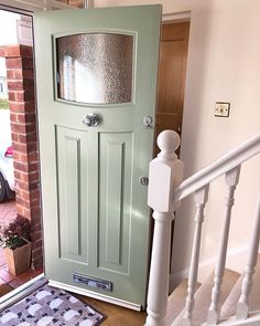 a green door with a glass window on the top and bottom part of it, next to a white stair case