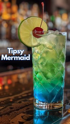 a colorful drink sitting on top of a bar next to a neon sign that says tipsy mermaid