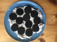 an oreo cookie and cream dessert in a blue bowl on a wooden table top