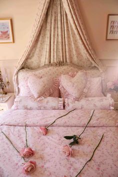 a bed with pink flowers on it and a canopy over the headboard in a bedroom