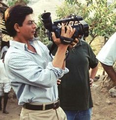 two men are standing in front of a camera and another man is holding a video camera