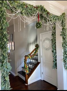 a staircase decorated with greenery and christmas wreaths