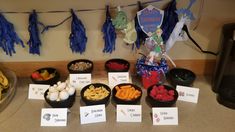 a table topped with bowls filled with food next to paper signs and bunting streamers