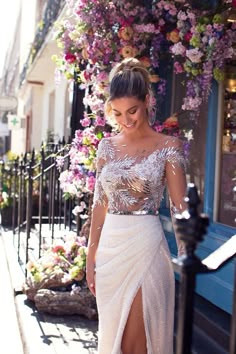 a woman in a white dress is walking down the street with her leg slit open