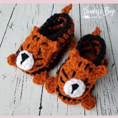 a pair of crocheted tiger slippers on top of a wooden floor