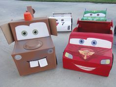 three cardboard cars are sitting on the ground next to each other, with faces painted on them