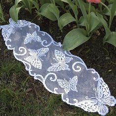 a lace doily laying on the ground next to tulips