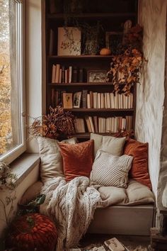 a couch with pillows and blankets in front of a bookshelf filled with books