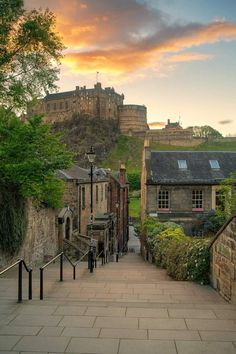 the sun is setting over an old castle like building on top of a hill with stairs leading up to it