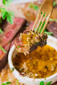 a piece of steak being lifted from a white bowl filled with sauce and garnished with parsley