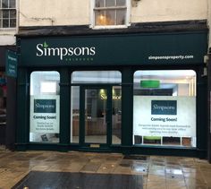 an empty storefront on a rainy day with signs in the front windows and doors