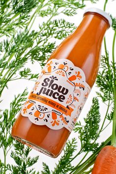 a bottle of slow juice next to some carrots