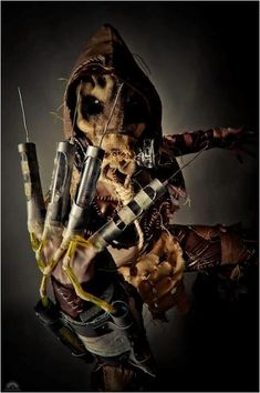 a creepy looking person holding some kind of knife in his hand with other items around him