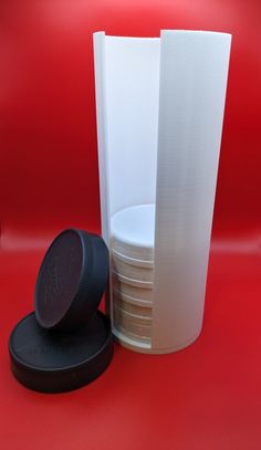 a stack of plates and a plastic cup on a red surface with a black lid