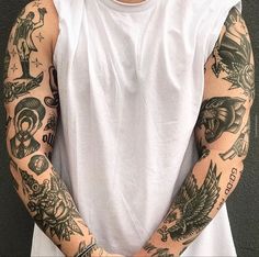 a man with many tattoos on his arm and arms, standing in front of a wall