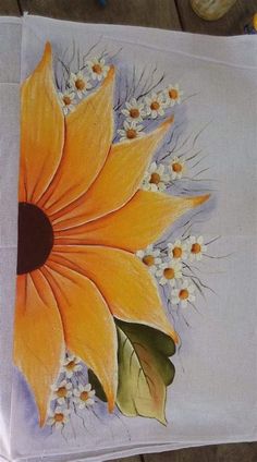 an orange flower is painted on a white cloth with yellow and white flowers in the center