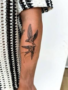 a woman's arm with a tattoo on it and a bird flying over her shoulder