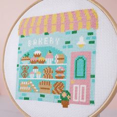 a cross stitch pattern with a store front and shelves filled with cakes, pies, and pastries