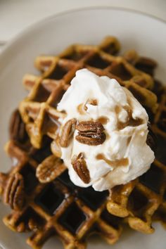 a waffle topped with whipped cream and pecans