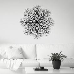 a living room with a white couch and black tree wall decal on the wall