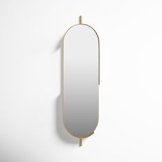 an oval mirror mounted on the wall with a gold frame and metal bar at the bottom