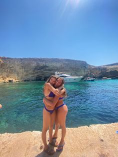 two women in bikinis hugging on the beach