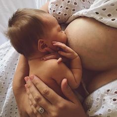 a woman is holding a baby in her lap and kissing it's face with both hands