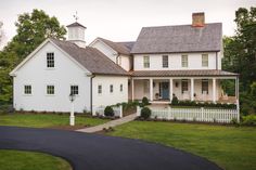 a large white house sitting on top of a lush green field