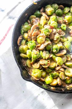 brussel sprouts and mushrooms in a cast iron skillet with a spoon