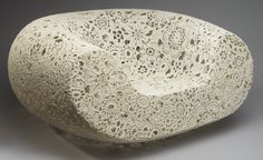 a large white rock sitting on top of a gray surface with holes in the middle