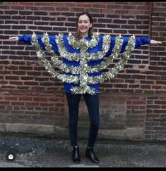 a woman standing in front of a brick wall wearing a blue and white striped sweater