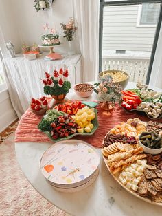 a table filled with lots of food on top of a white table cloth next to a window