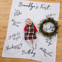 a baby laying on top of a blanket next to a wreath