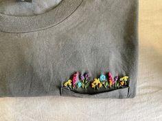 a gray t - shirt with embroidered flowers on it