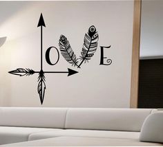 an arrow with two feathers and the word love on it is next to a white couch