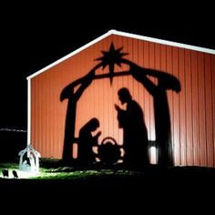 the shadow of two people in front of a christmas nativity scene on a barn