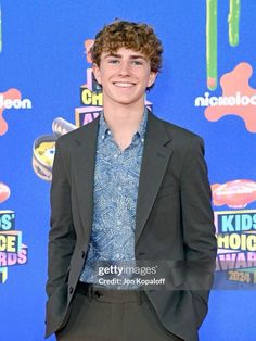 a young man in a suit and tie posing for a photo on the red carpet