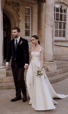 a bride and groom standing in front of an old building with columns on either side